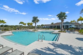 a swimming pool with palm trees and a building in the background